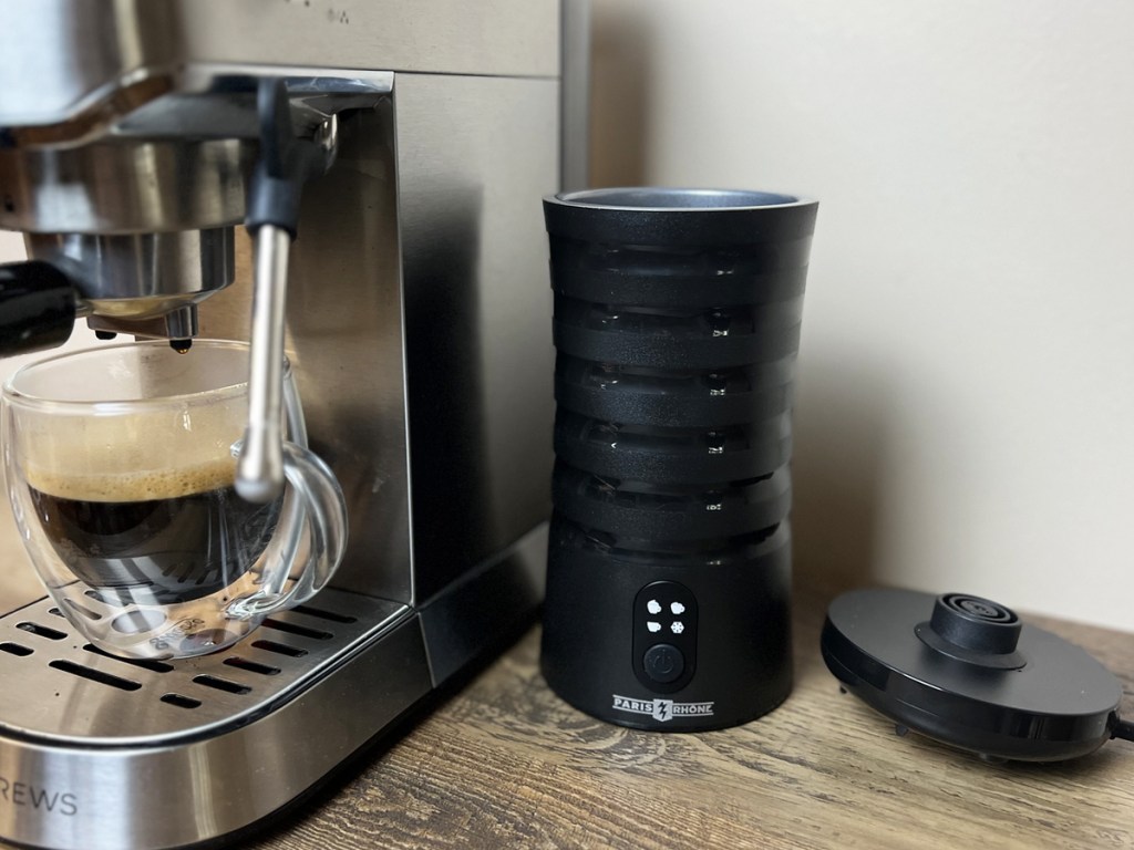 black milk frother sitting next to cappuccino machine