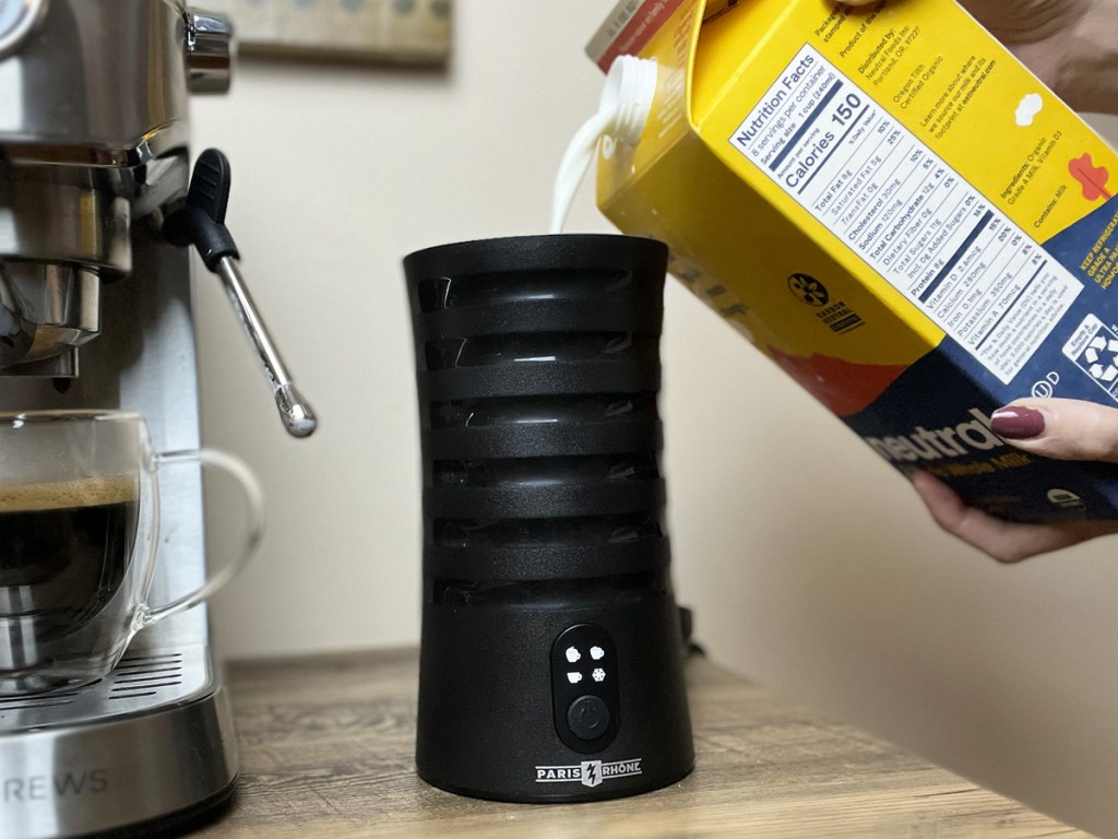 pouring milk into a black milk frother