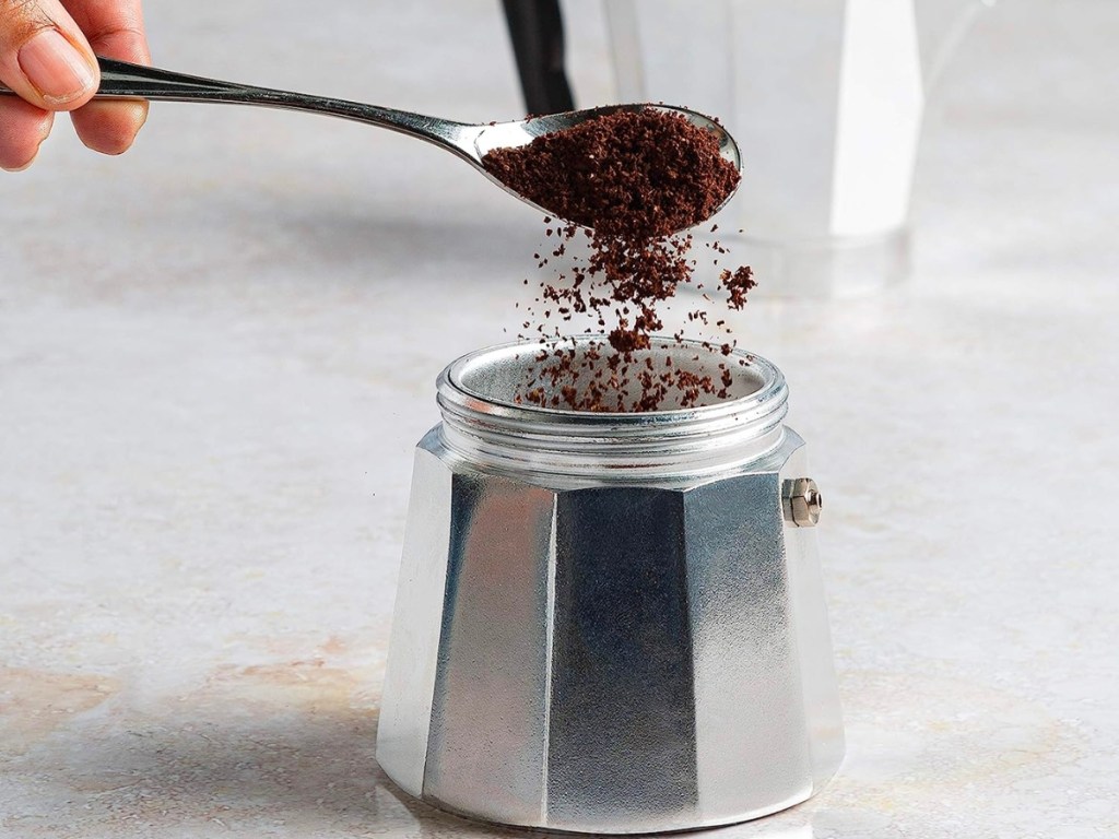 coffee grounds being poured into primula moka pot