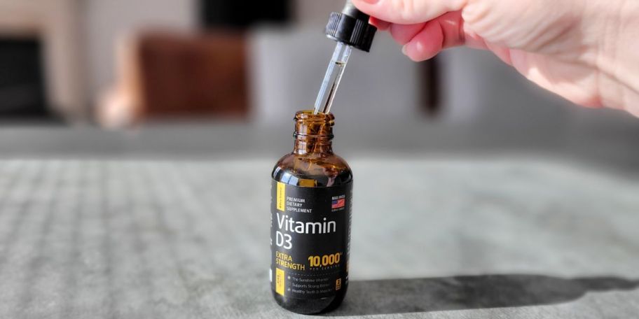 person taking dropper from Vitamin D3 bottle