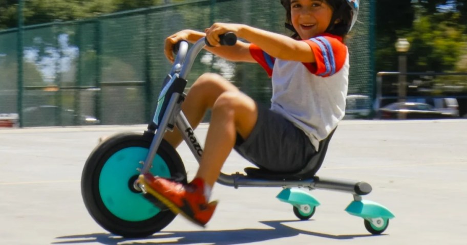 little boy riding on a low rid tricycle with teal and black accent colors