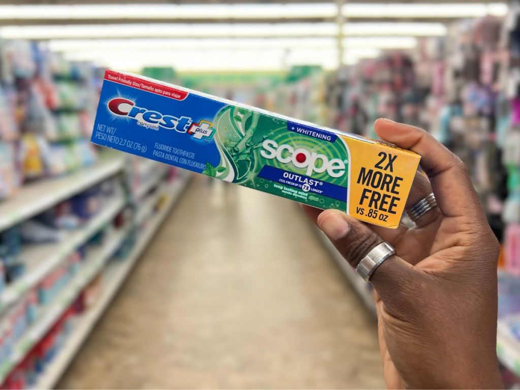 A hand holding a toothpaste box