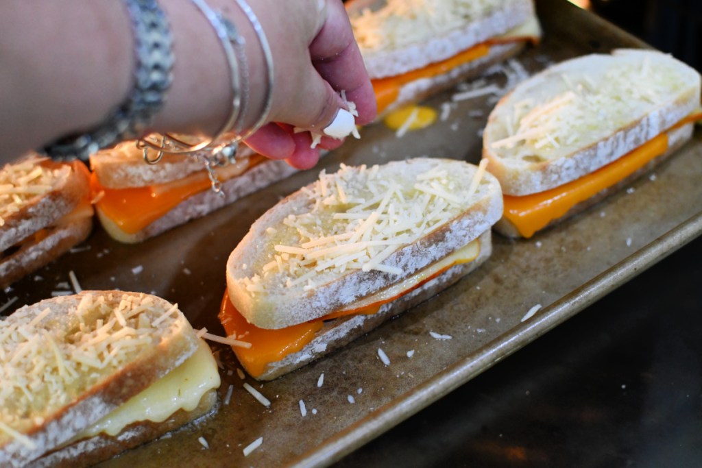 adding parmesan to the tops of grilled cheese