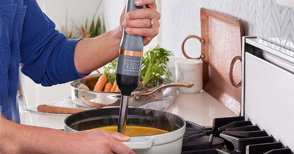 hand using immersion blender in pot of soup