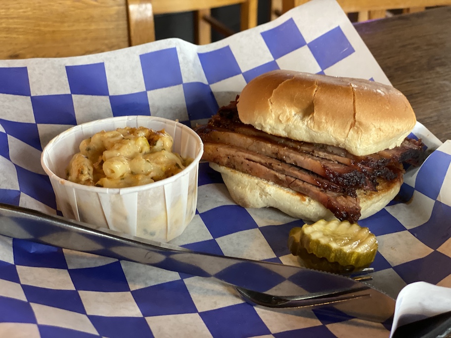 steak sandwich and cup of mac n cheese on blue and white checked paper