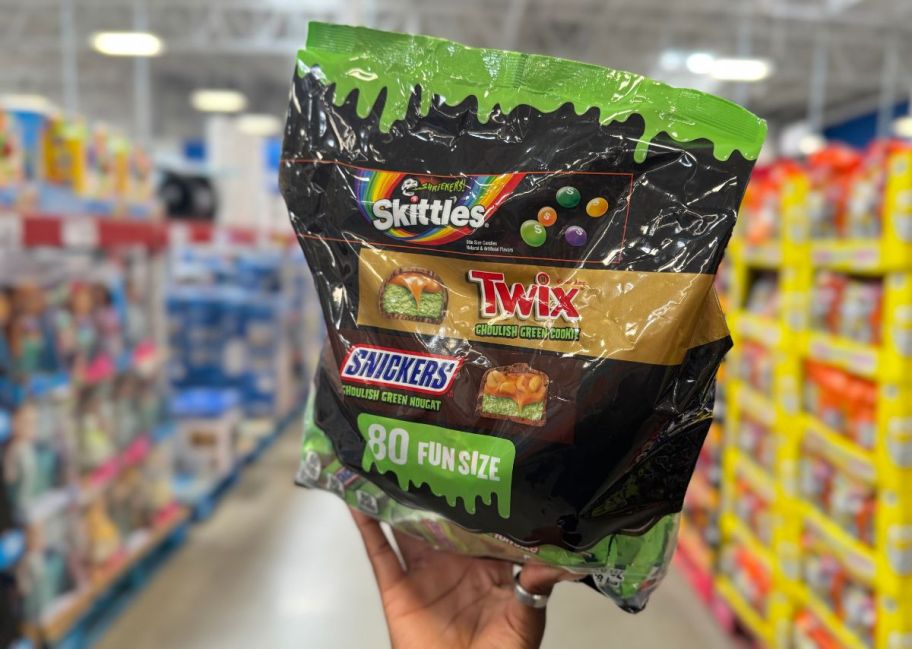 a womans hand holding a bag of assorted candies 