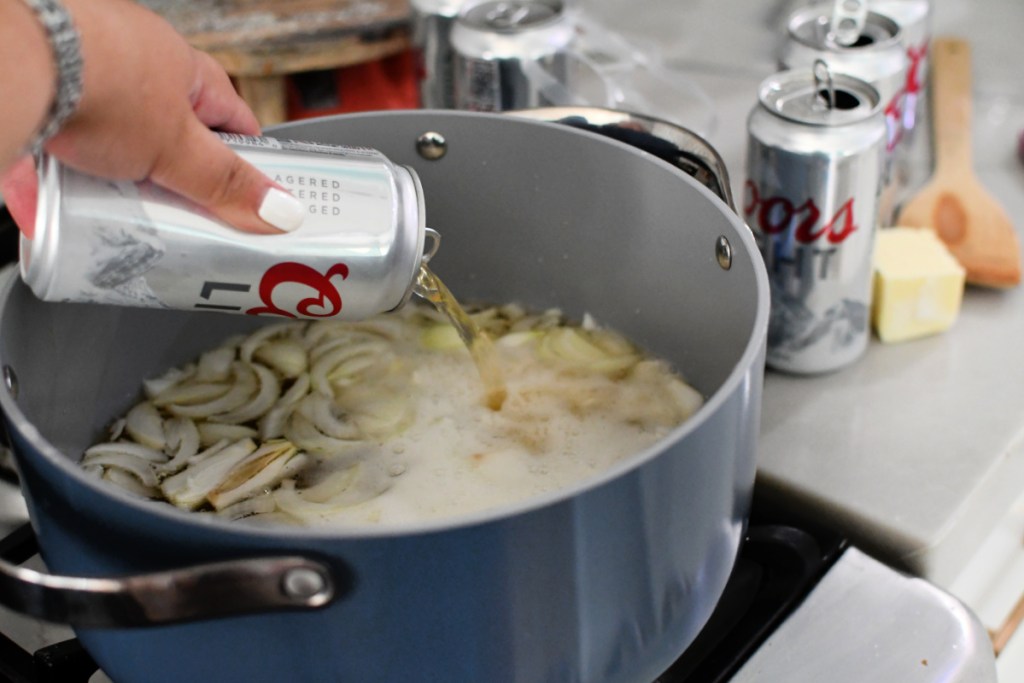 simmering brats on the stove with onion and beer