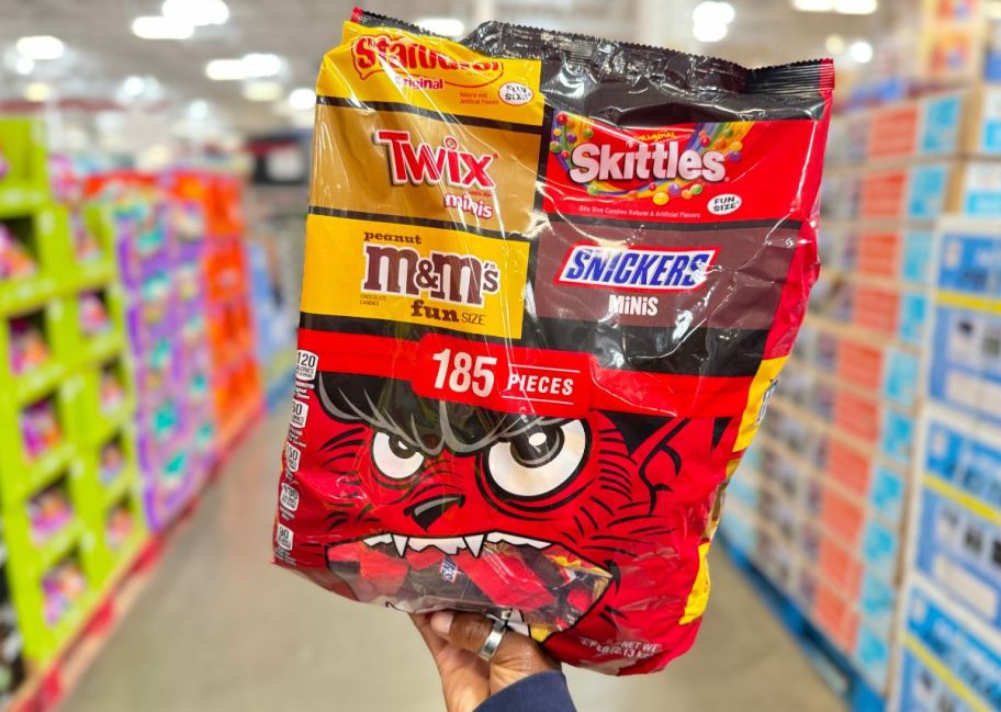 a womans hand holding a 185 count bag of halloween candies