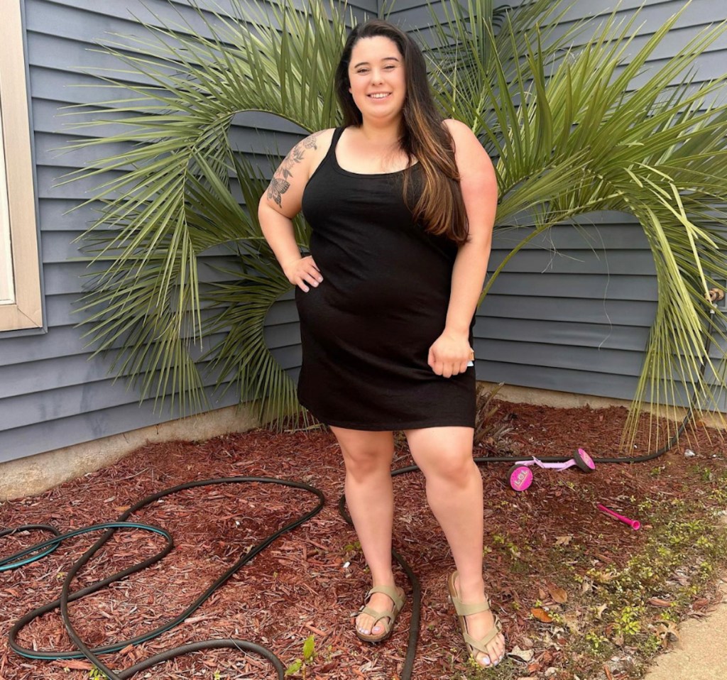 woman wearing black sundress in front of mulch bed with palm tree