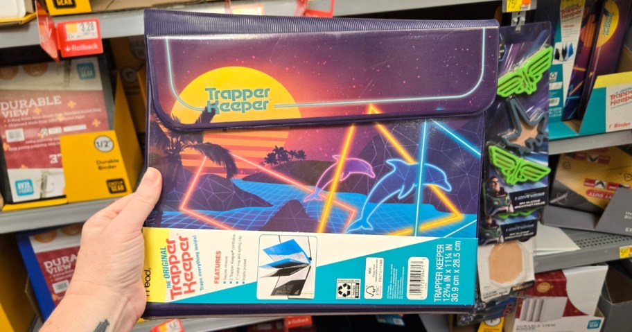 hand holding a Trapper Keeper with neon dolphindesign