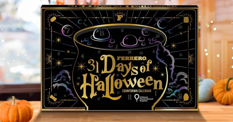 Ferrero Halloween Countdown Calendar in a black and gold box on a table with small pumpkins