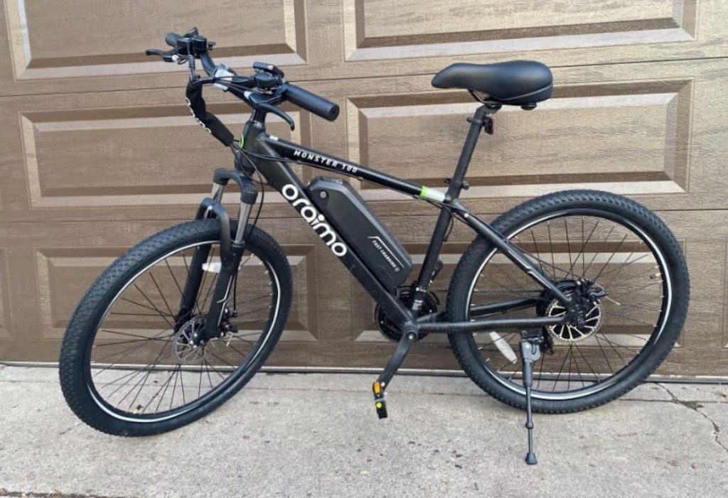 black electric bike sitting in front of brown garage door