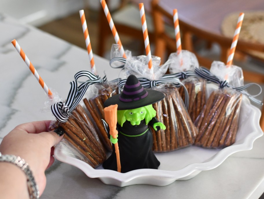 Hand holding a platter of pretzel broomsticks, non candy Halloween treats