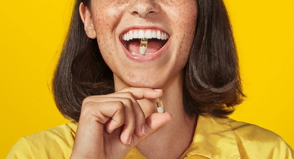 Woman with ritual multivitamin in her teeth and on her hand