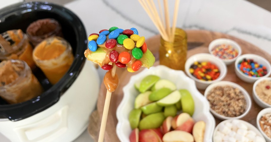 caramel apple slice dipped in candy on a stick 