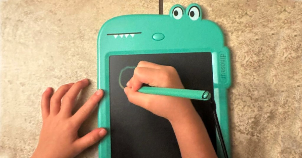 child drawing on dinosaur doodle board