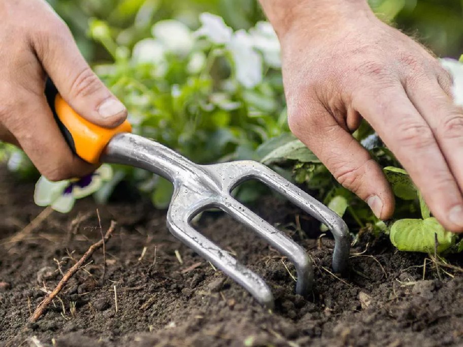hand getting in the dirt using a Fiskars Ergo Cultivator