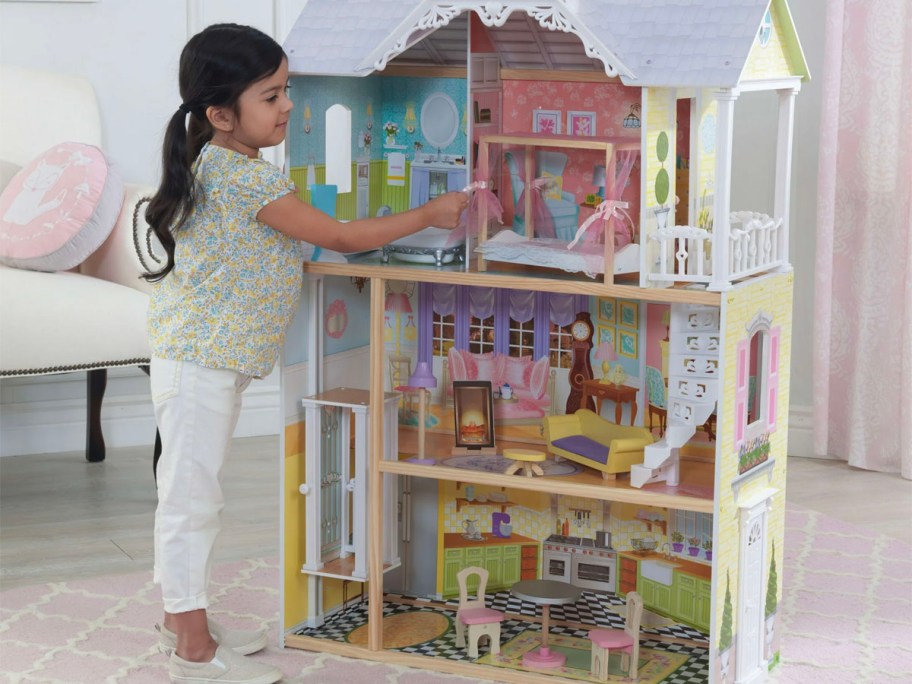 girl playing with wooden dollhouse