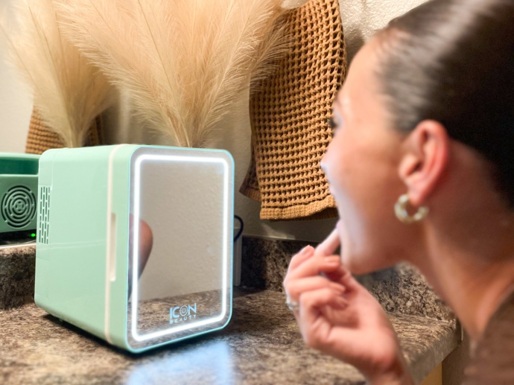 woman looking in mirror on mini fridge