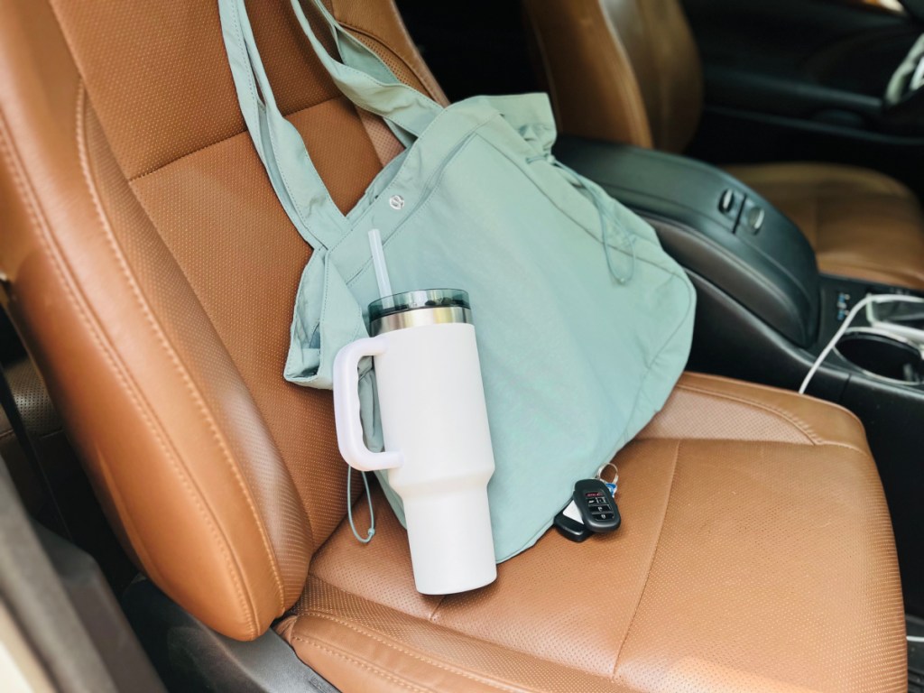 white tumbler next to blue bag in car