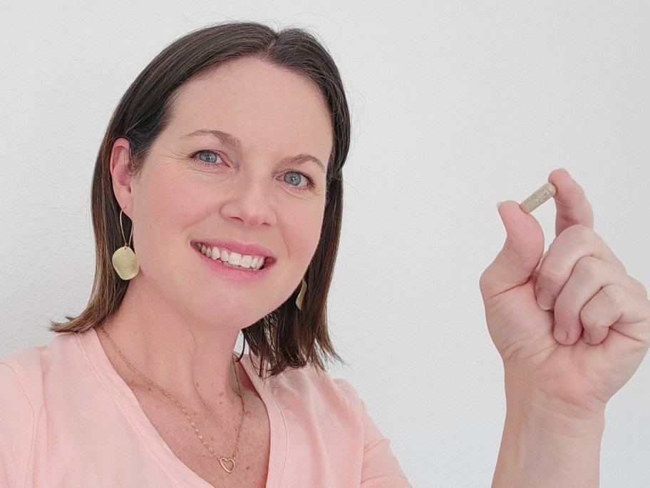 woman in pink shirt holding raw science vitamin