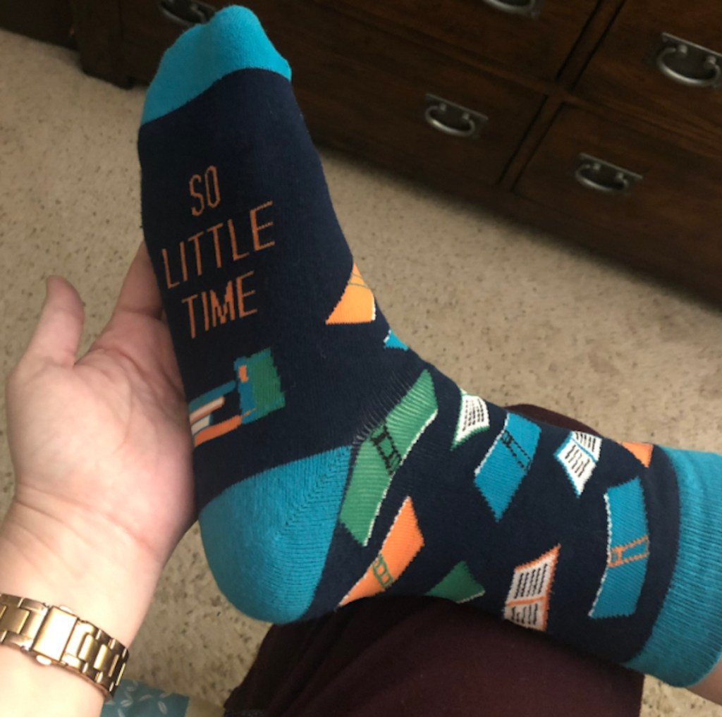 hand holding up foot with so many books on socks