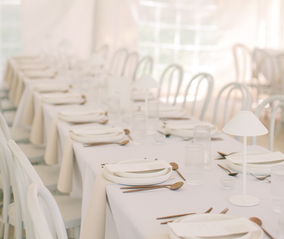 long wedding table with white dishes and lamps