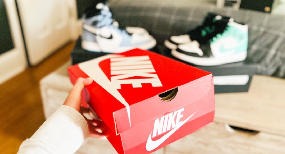 woman holding nike shoe box with nike shoes displayed in the background