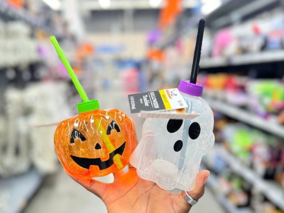 hand holding a small light up jackolantern and ghost tumblers with straws