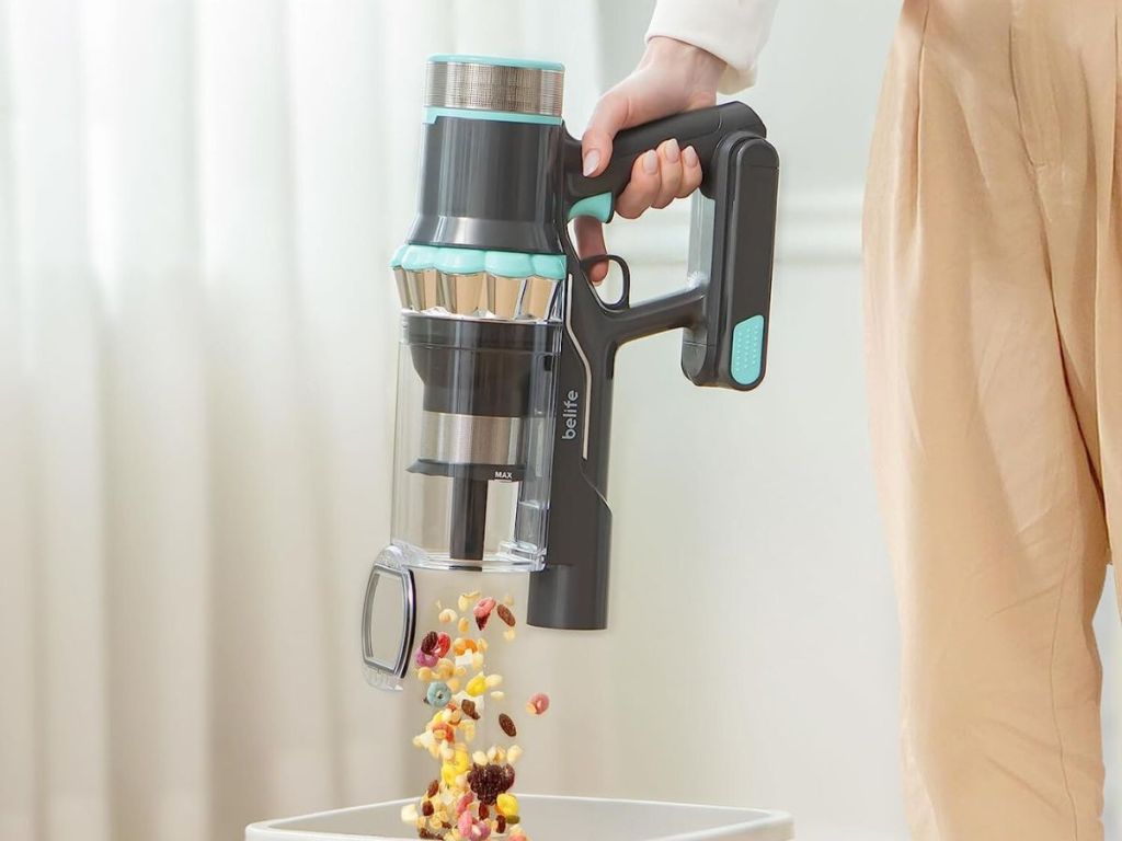 person emptying handheld vacuum into trash