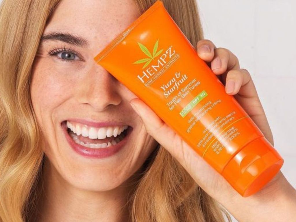 A woman with a bottle of Hempz Yuzi & Starfruit self tanner 