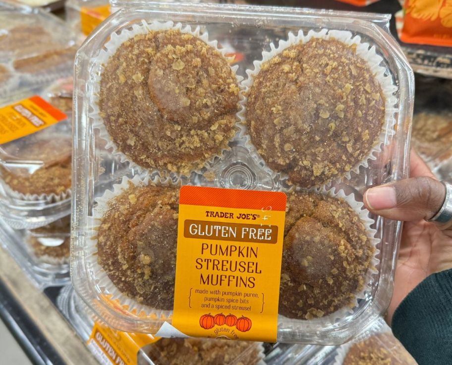 a woman's hand holding a box of pumpkin streusel muffins