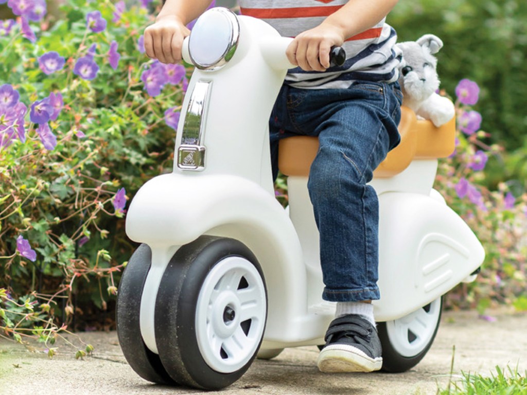 boy riding on a white step2 scooter