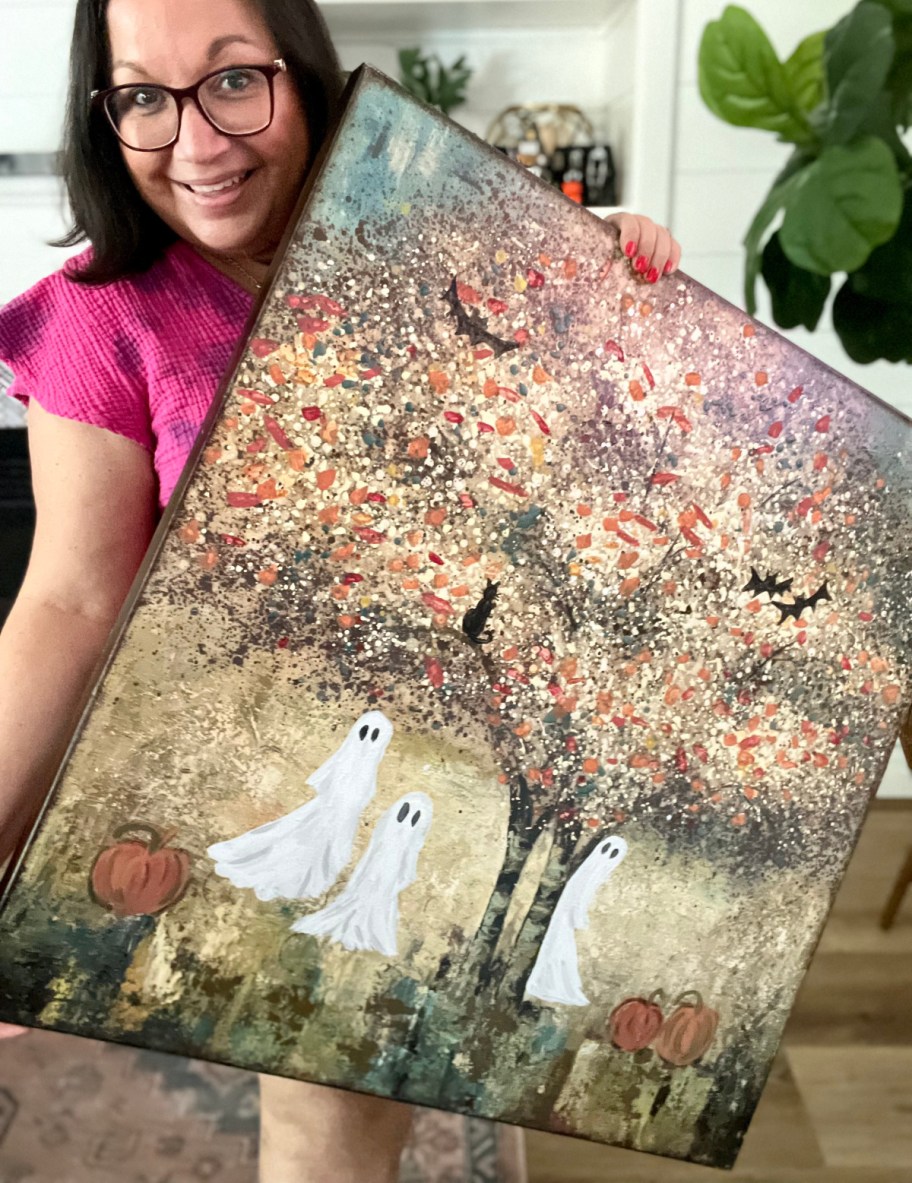 woman holding a diy thrift store ghost painting 