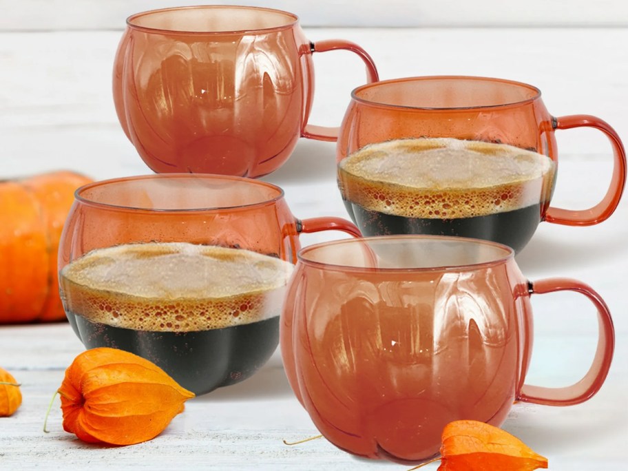 four orange glass pumpkin mugs on table