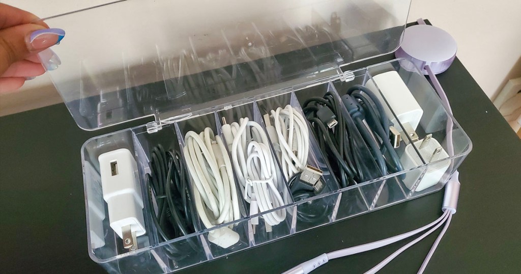 clear cable storage box full of chargers on table