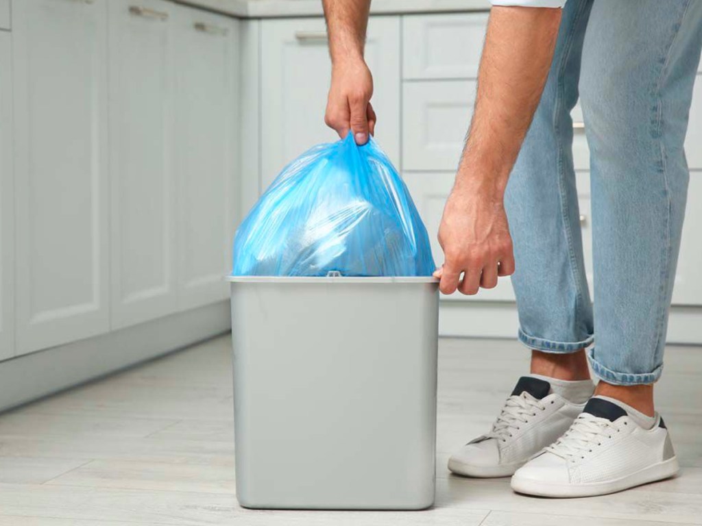 hand pulling trash bag out of trash can