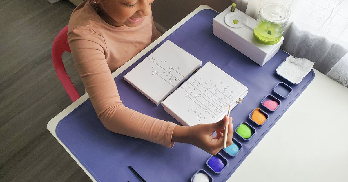 girl painting using purple painting mat