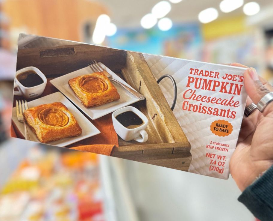 a womans hand holding a box of pumpkin cheesecake croissants