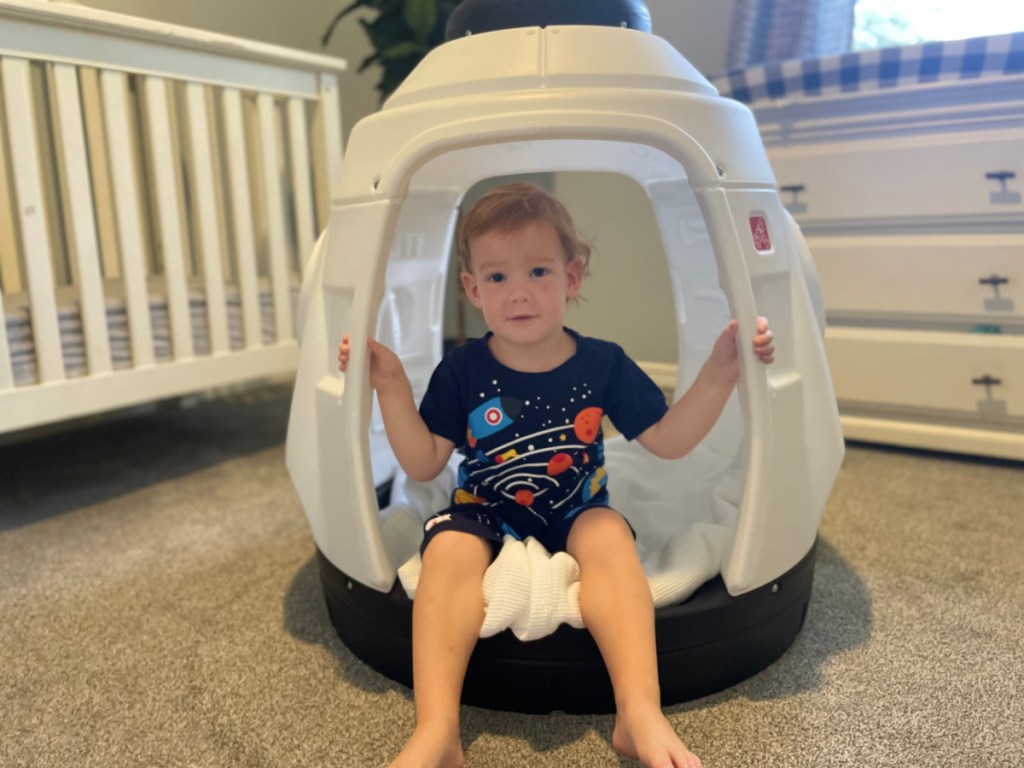 boy holding handles of rocket ship playhouse