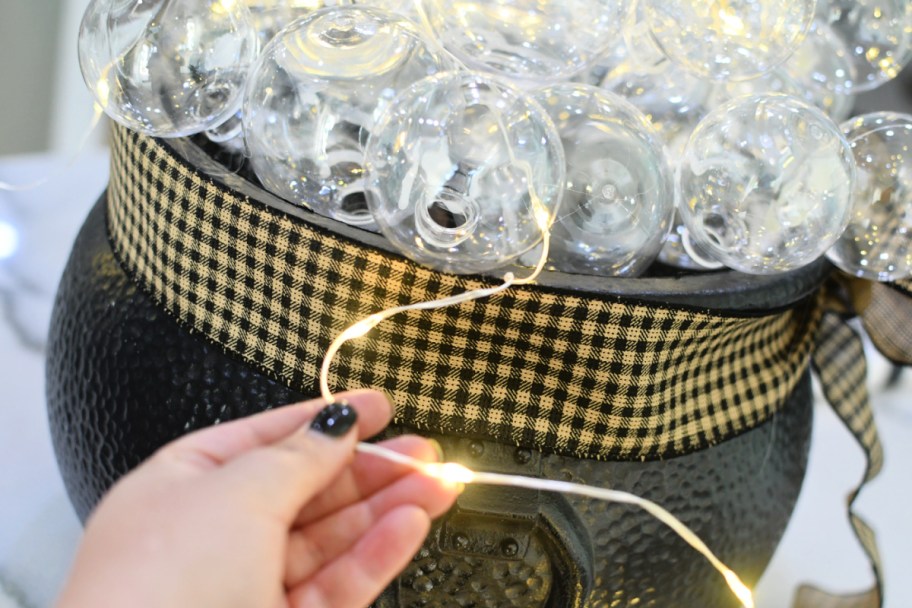 weaving fairy lights in diy cauldron