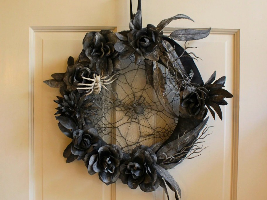 black and grey floral Halloween wreath with spiders and a web on a white door