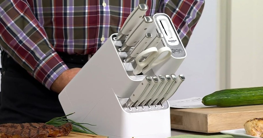 a white Ninja knife block set with knives and kitchen sheers in it on a table, man standing behind the set