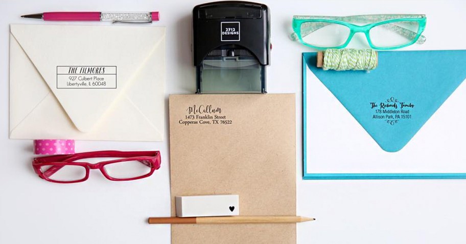 self ink stamp with envelopes, glasses and pens on table