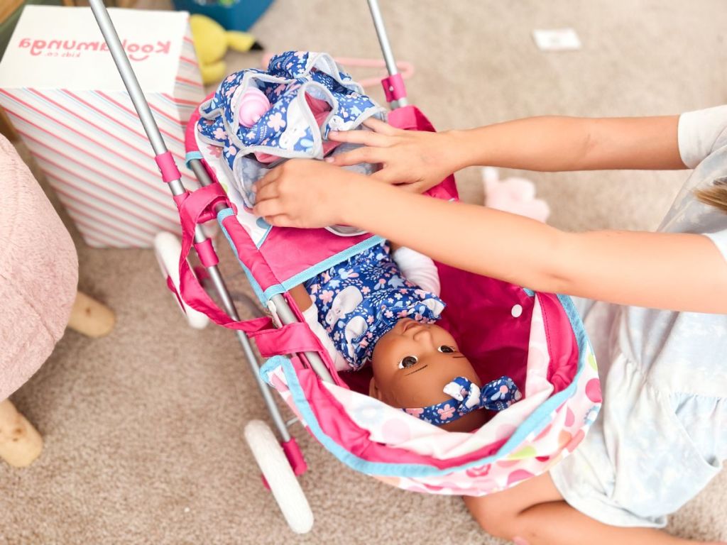 little girl playing with a Kookamunga baby doll in a Kookamunga baby doll stroller