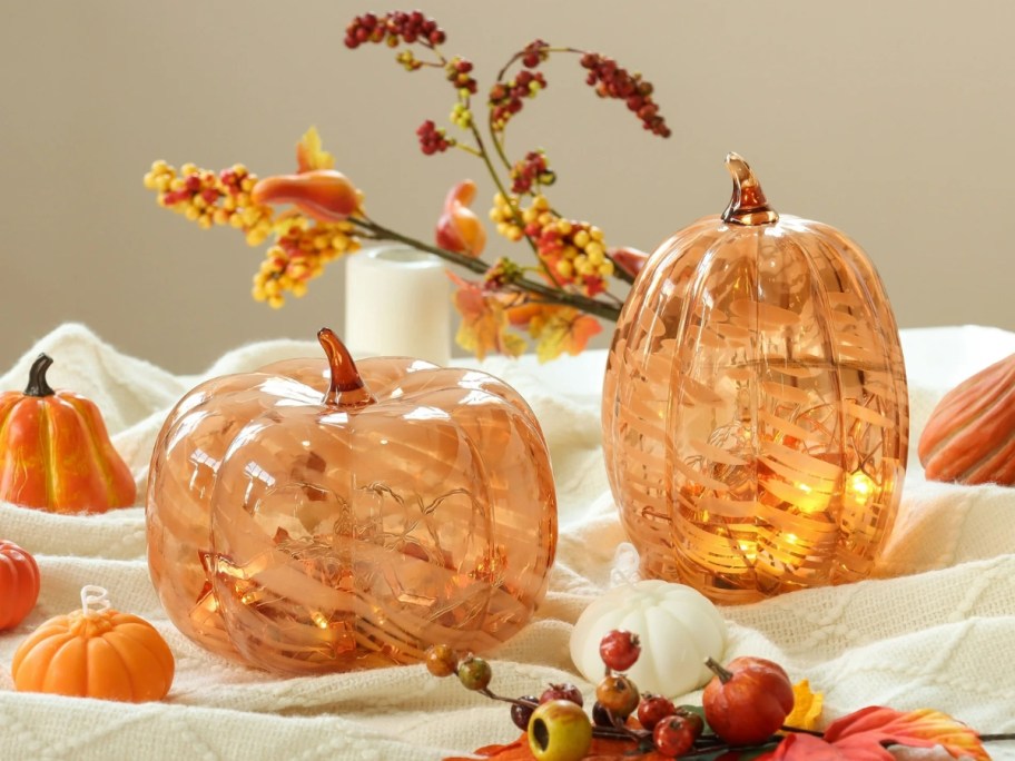 orange marbled glass pumpkins on a table with fall decor