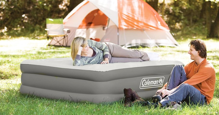 woman laying on top of a Coleman Air Mattress in front of tent