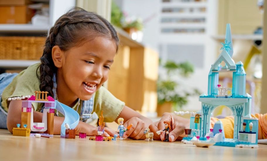 a girl playing with the elsas castle building set