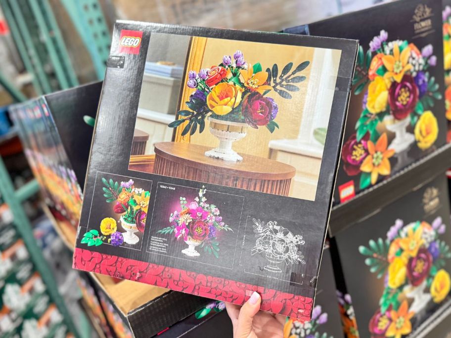 A person holding a box of LEGO flowers in a store