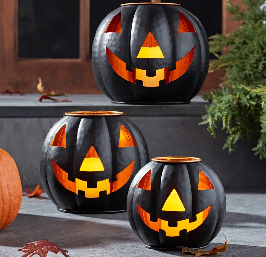 3 black metal lighted jack-o-lanterns on porch step